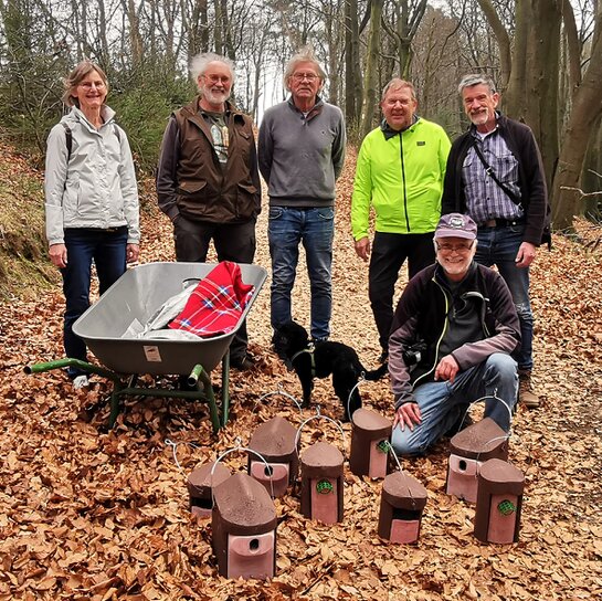 Vereinsmilglieder posieren vor den fertigen Nisthilfen im Wald